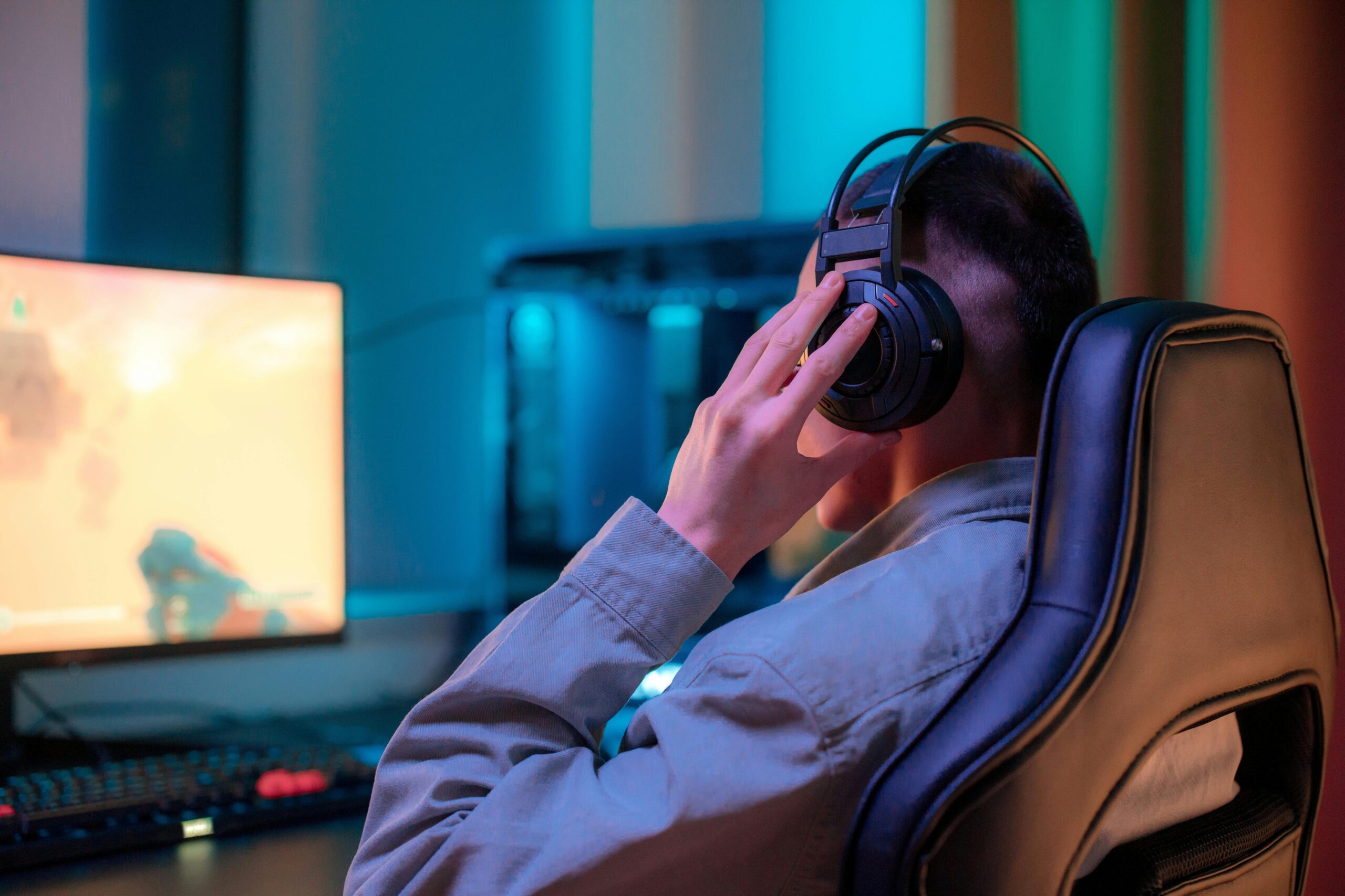 Man sitting at PC in gamer chair with high-end headphones